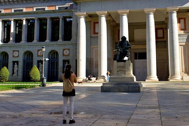 a woman taking a picture of a statue in front of a building