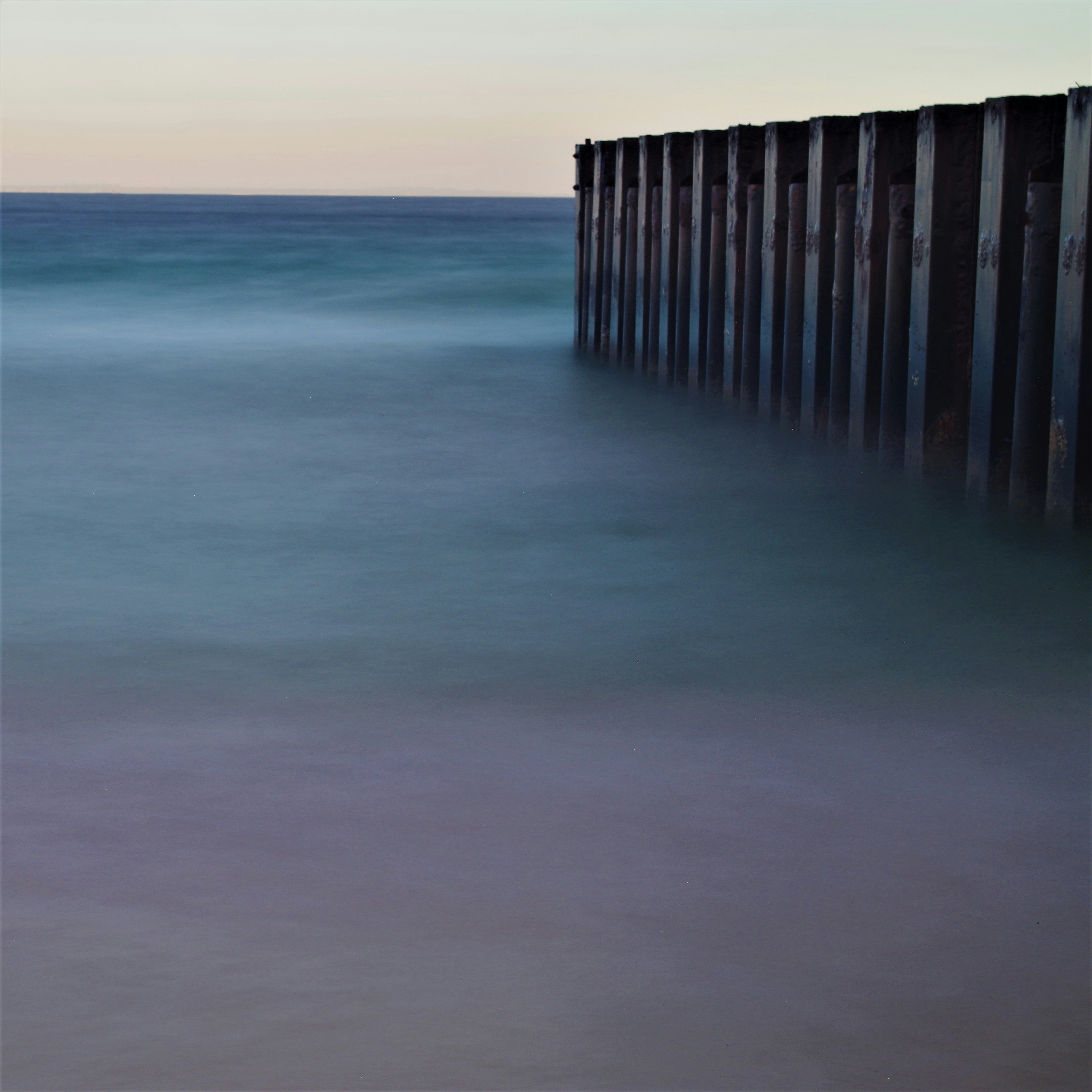 a long exposure photo of the ocean and a pier