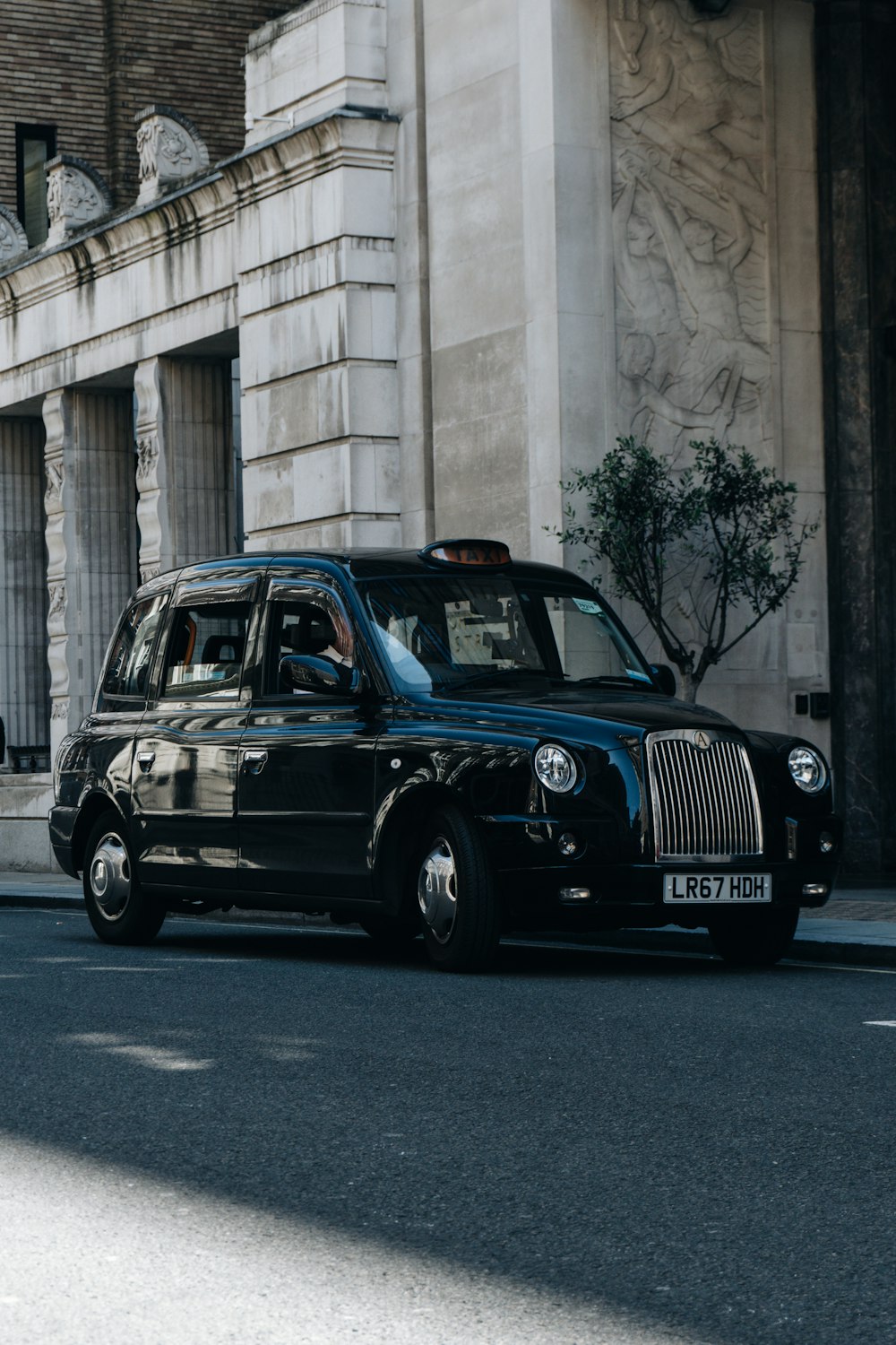 a black taxi cab driving down a street next to a tall building