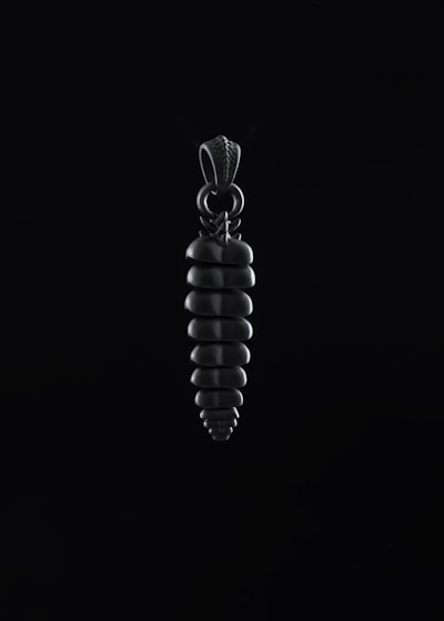 Close-up of a sleek Atalaia pendant glowing softly against a deep blue-black background.