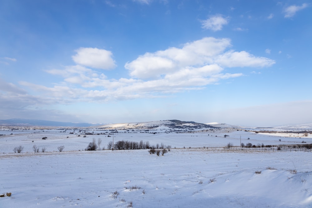 a snow covered field with a mountain in the distance