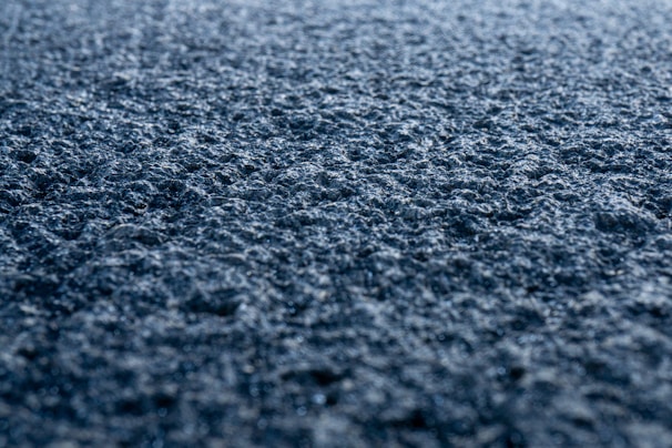Close-up of gritty asphalt texture illuminated by electric orange light in a dark workshop.