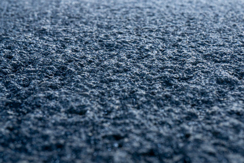 Close-up of freshly sealed asphalt driveway with a smooth, glossy finish under soft natural light.