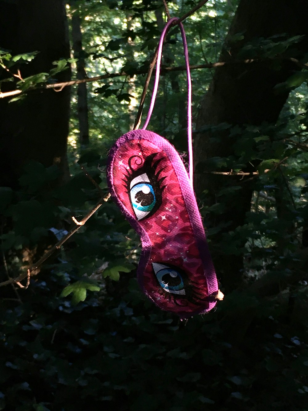 a stuffed animal hanging from a tree in a forest