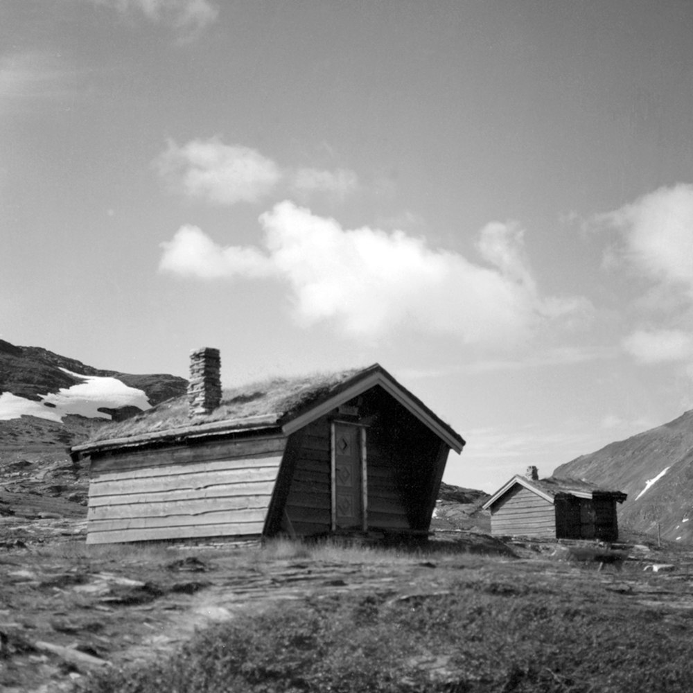 a black and white photo of a cabin in the mountains