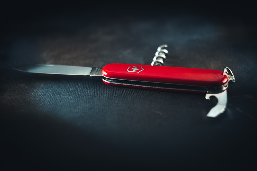 テーブルの上に座っている赤いポケットナイフ