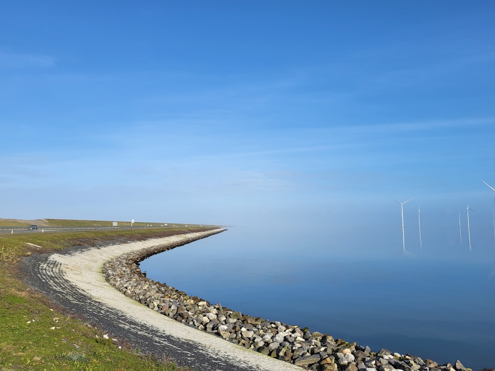 a view of a body of water with a wind farm in the background