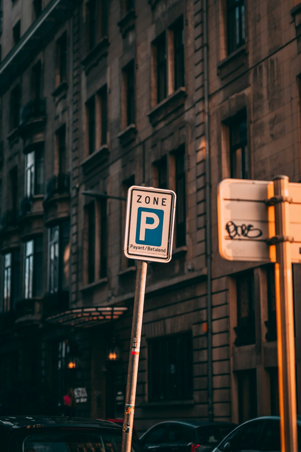 a parking sign on a pole in front of a building