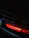 Close-up of a sleek BMW M4 with glowing blue and red light accents under dark ambient lighting.
