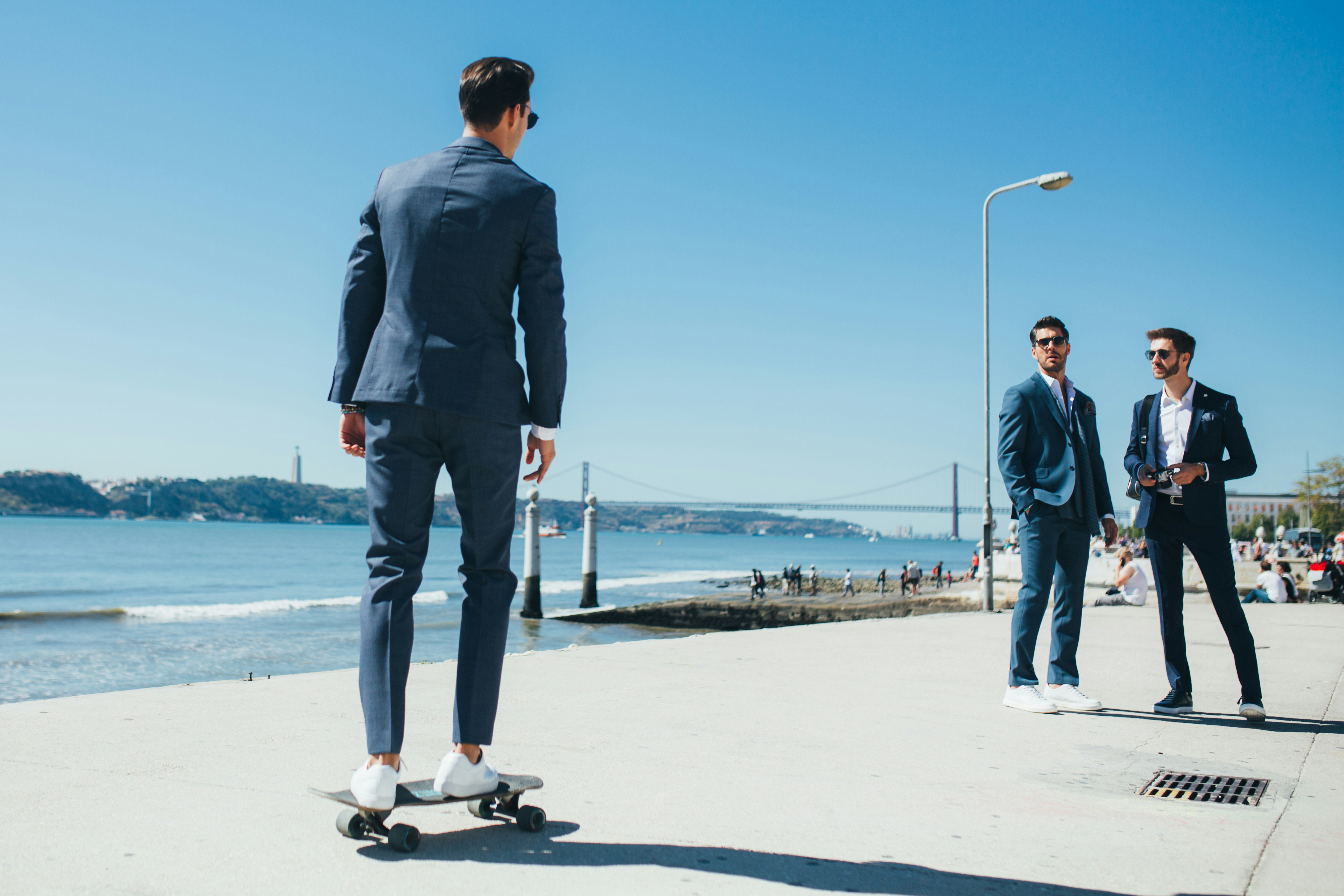 A man in a suit riding a skateboard on a sidewalk
