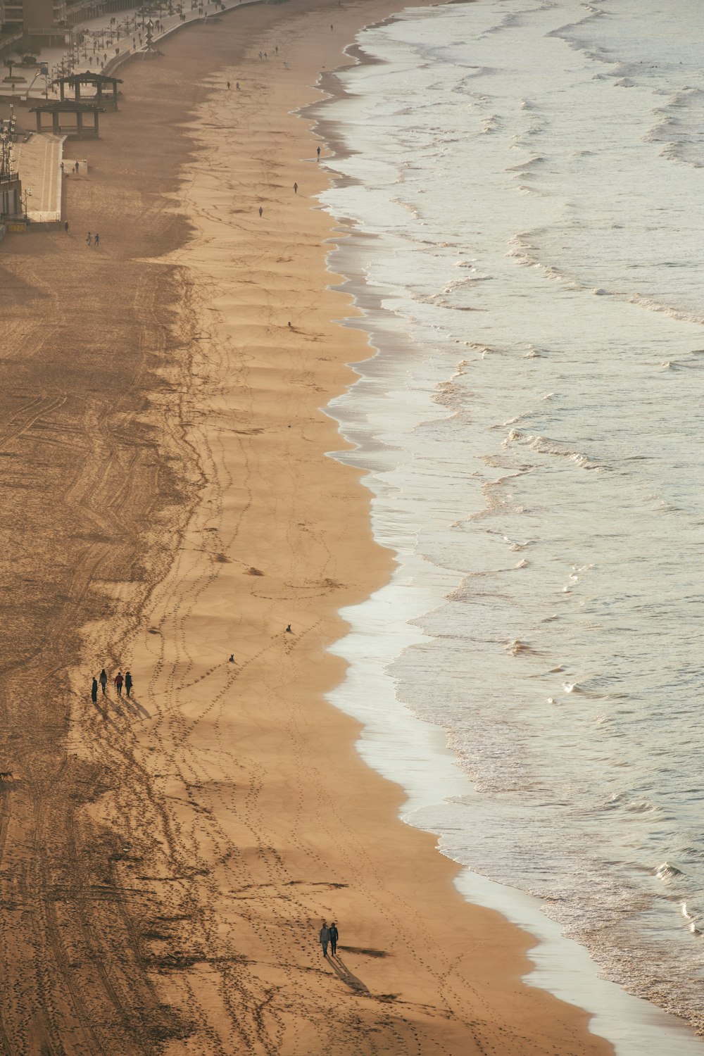 a group of people walking along a beach next to the ocean