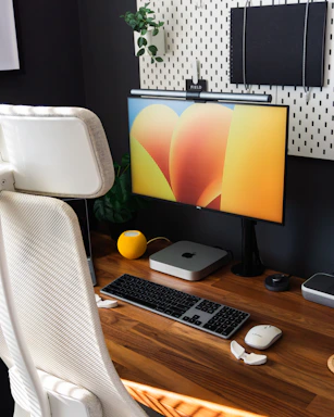 Modern office workspace with orange accents and smart home devices on the desk.