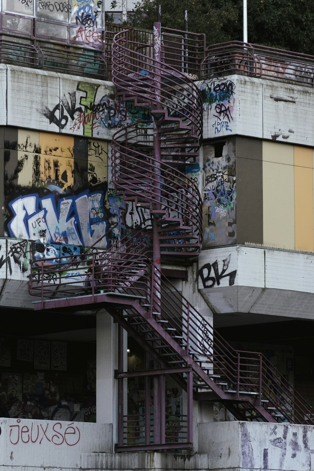 uma escada em espiral em frente a um edifício com grafite sobre ele