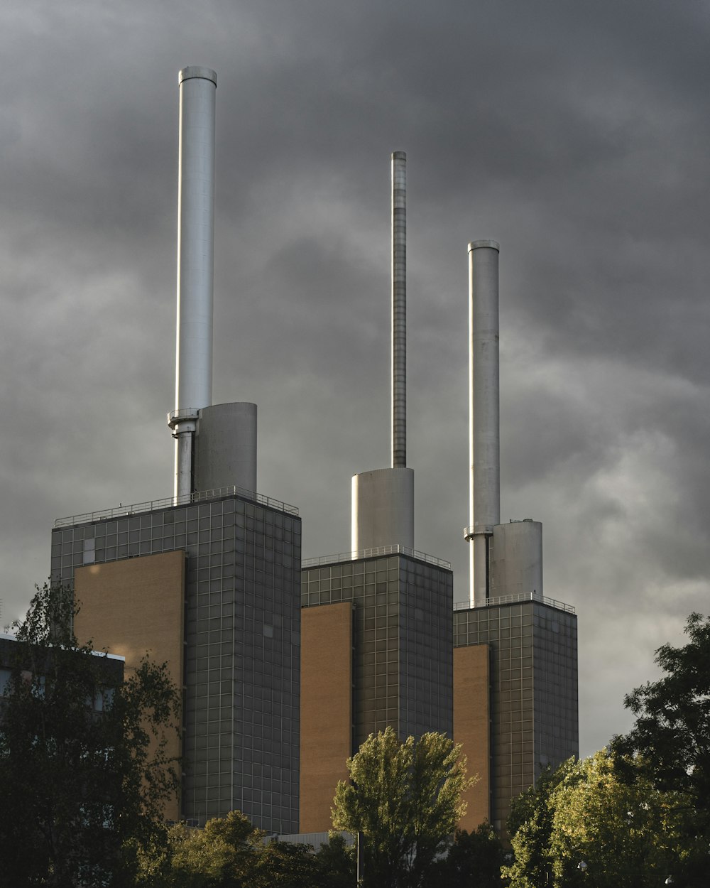 a group of smoke stacks in front of a cloudy sky
