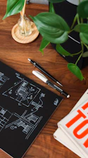A sketchbook with logo ideas and colorful pencils on a wooden table
