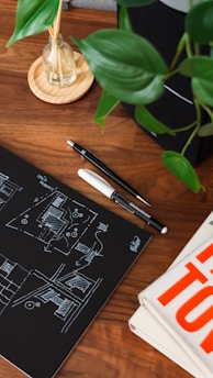 Designer sketchbook with hand-drawn interior concepts and color palettes on a wooden desk.