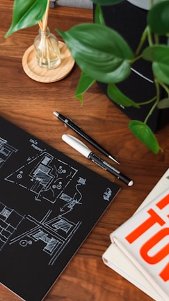 Sketches and colorful kitchenware designs spread out on a wooden table, capturing their creative process.