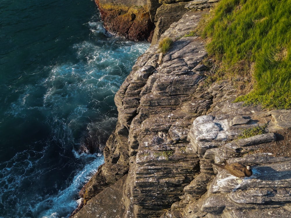an aerial view of a rocky cliff with a body of water