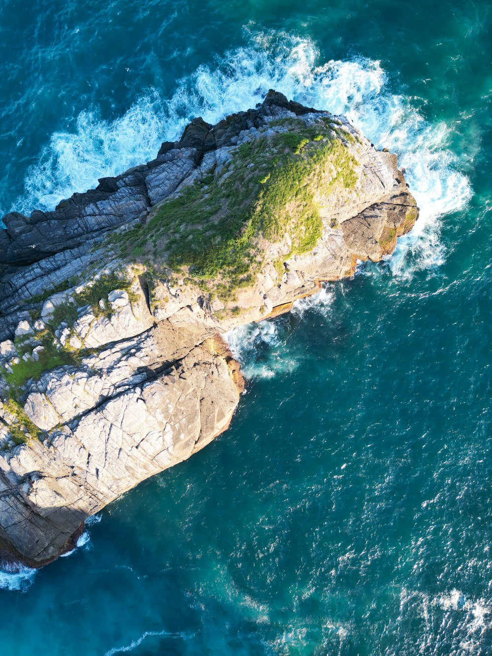 an aerial view of a rock outcropping in the ocean