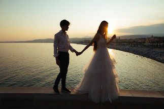 Elegant couple holding hands by the shore of Lake Como at sunset.