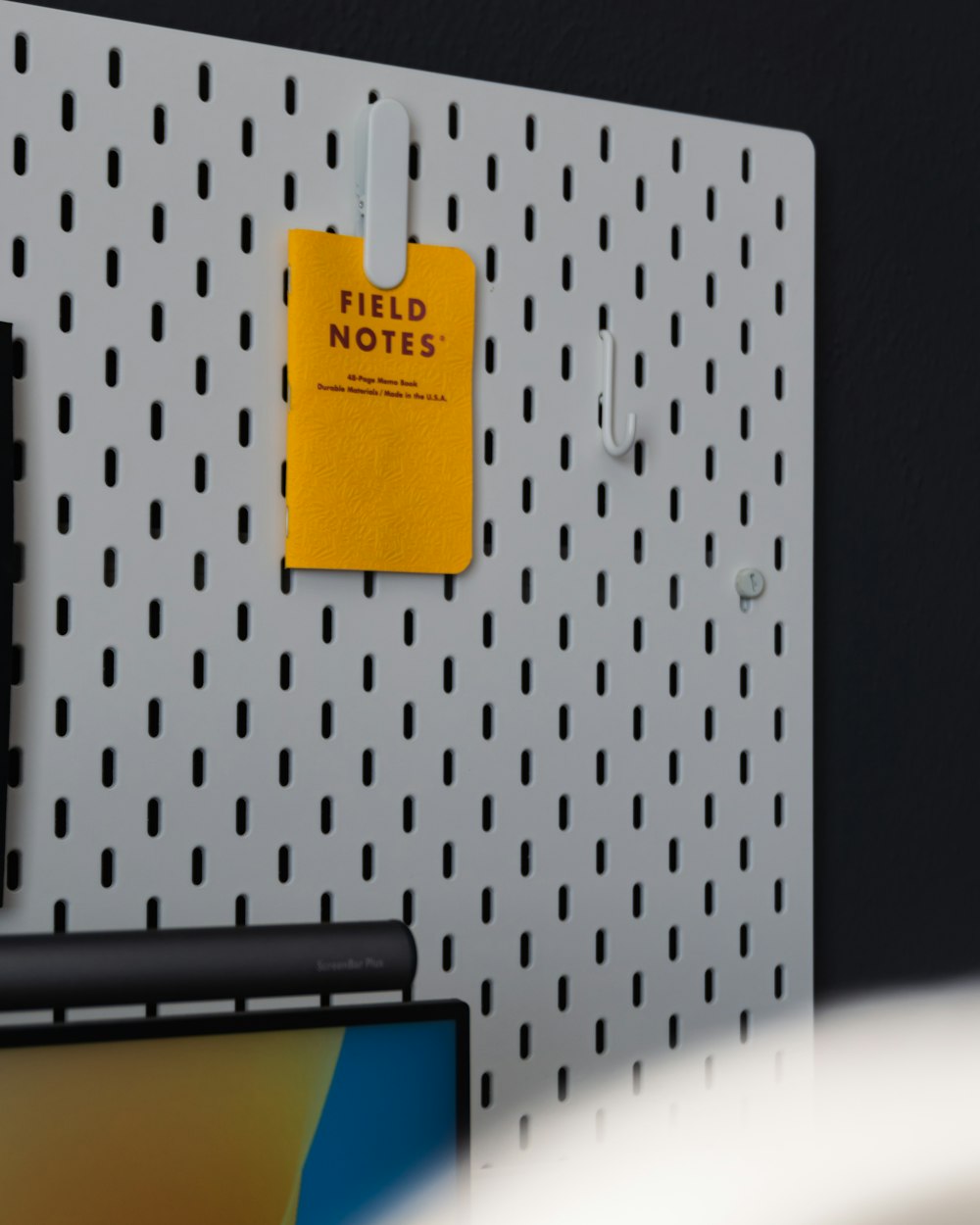 a yellow sticky note pinned to a white pegboard