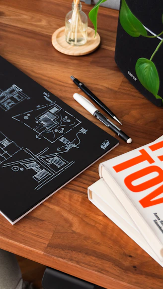 a wooden table topped with books and a pen