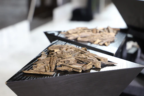 Close-up of rich, dark agarwood chips arranged artistically on a wooden surface.