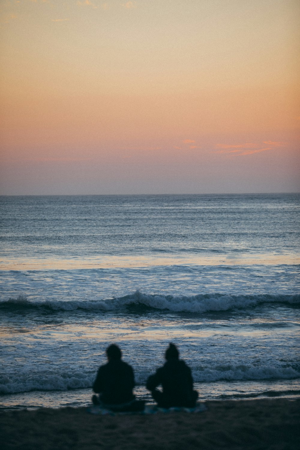 a couple of people sitting on top of a sandy beach