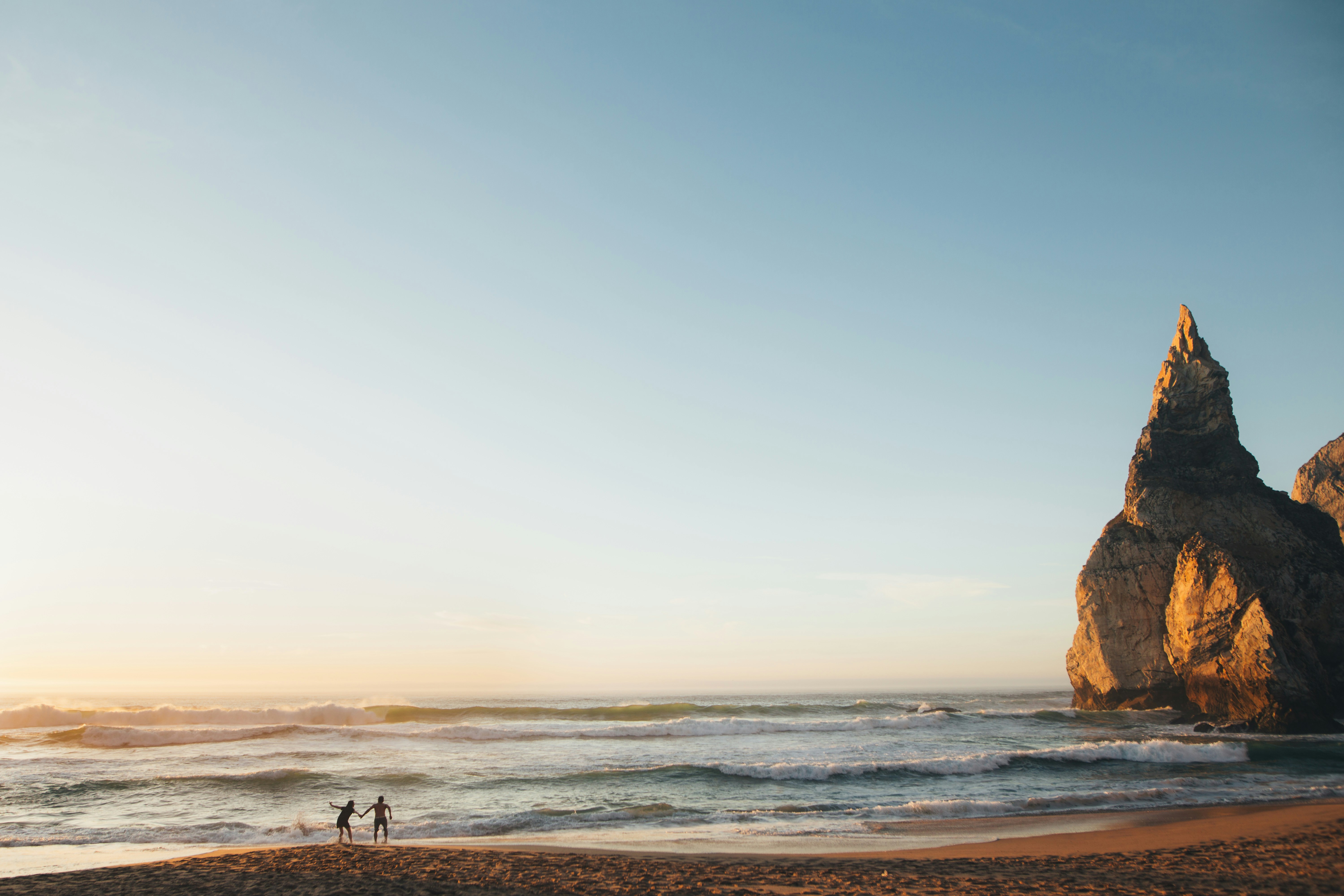 ein paar Leute stehen auf einem Sandstrand