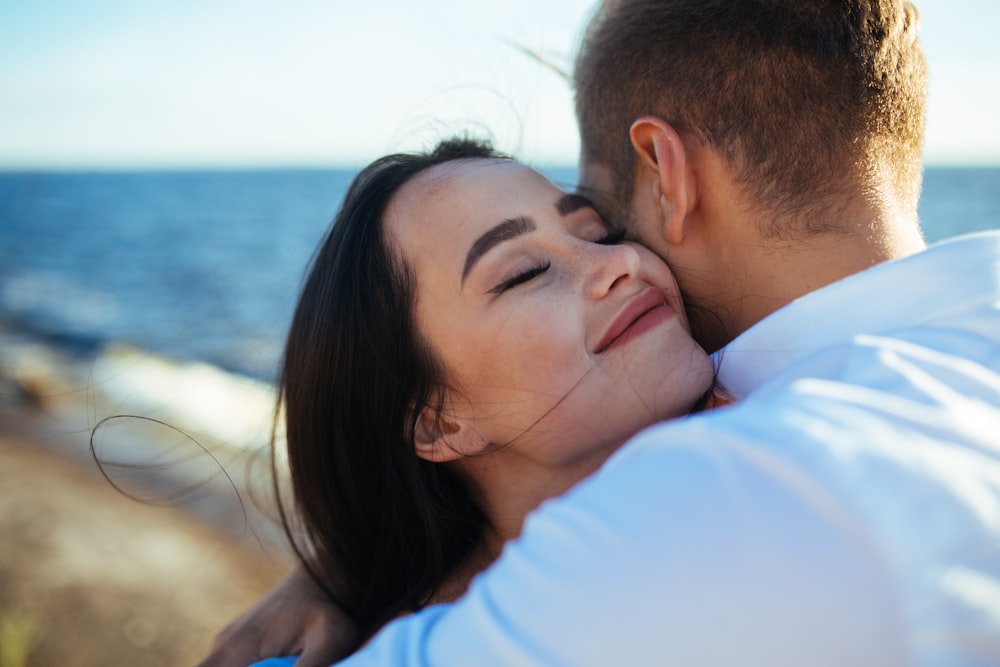 a man and woman embracing each other near the ocean