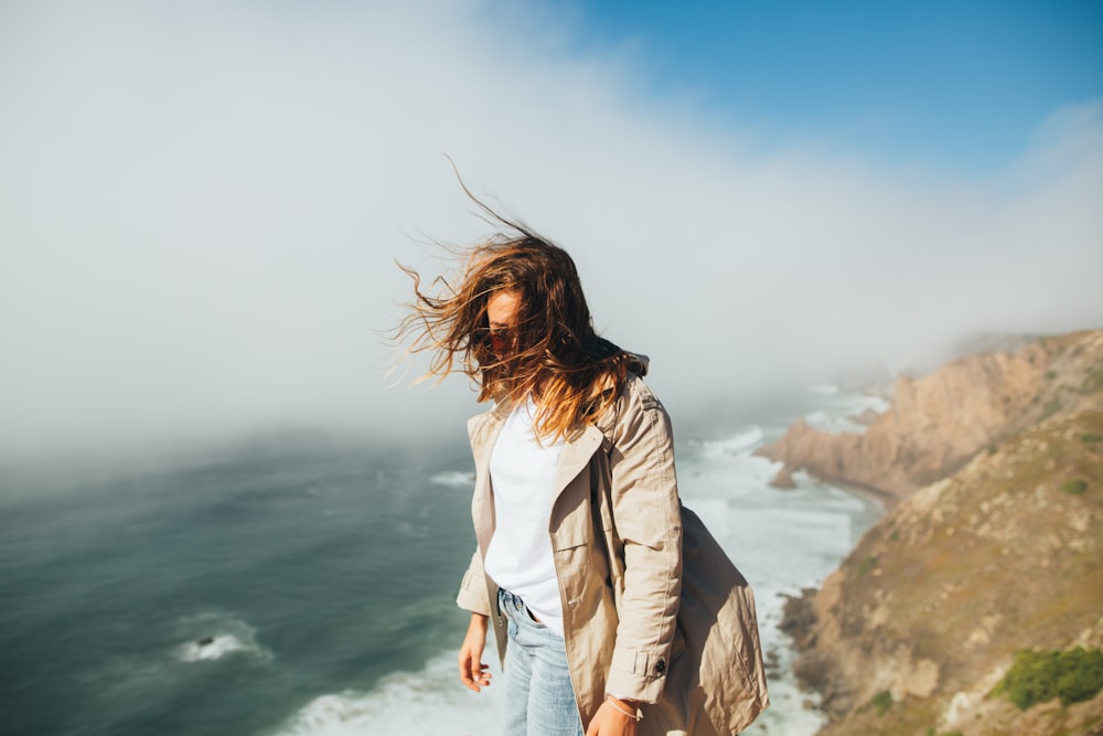 a woman standing on top of a cliff near the ocean