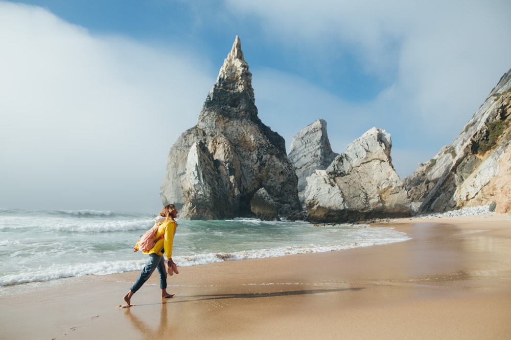 a man walking along a beach next to the ocean