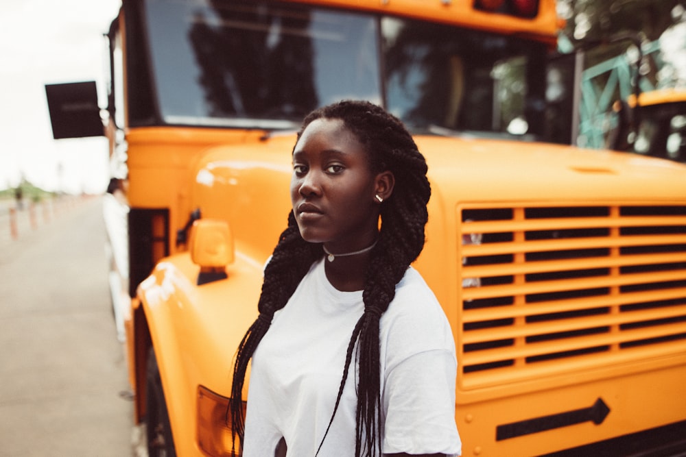 a woman standing in front of a yellow school bus