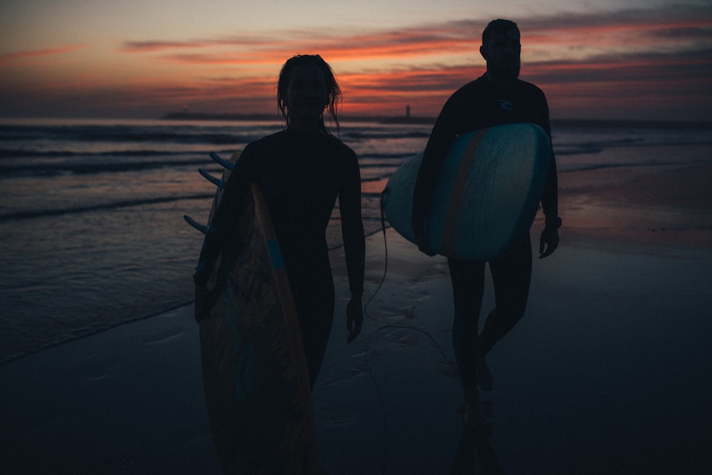 a couple of people that are holding surfboards