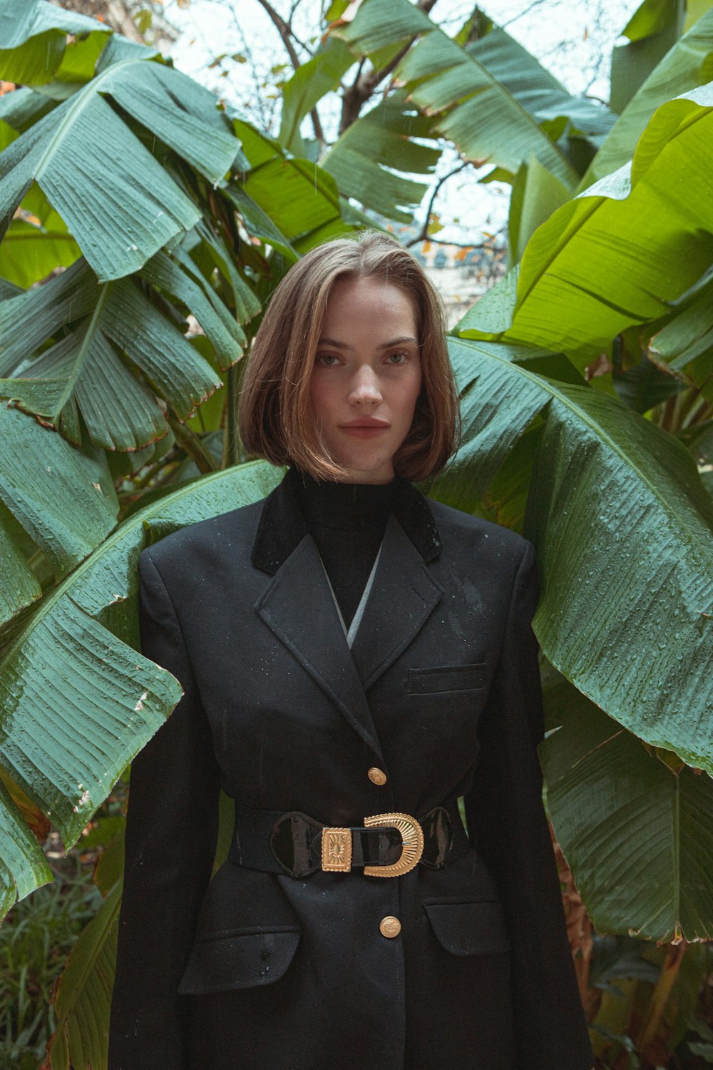 a woman standing in front of a bunch of leaves