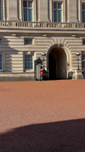 A professional security officer standing alert outside a modern office building in the UK.