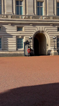 A vigilant security guard in classic uniform overseeing a corporate building entrance at dusk.