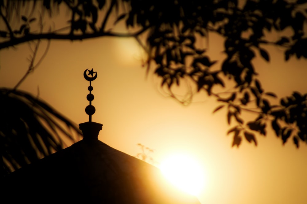 the sun is setting behind a building with a cross on top