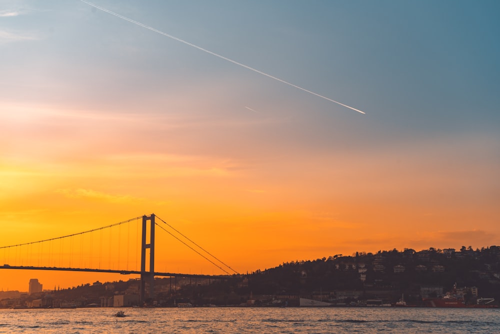 the sun is setting over a bridge and a body of water