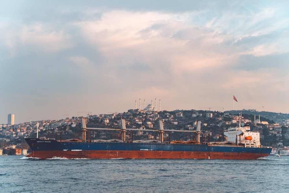 a large ship in the water with a city in the background