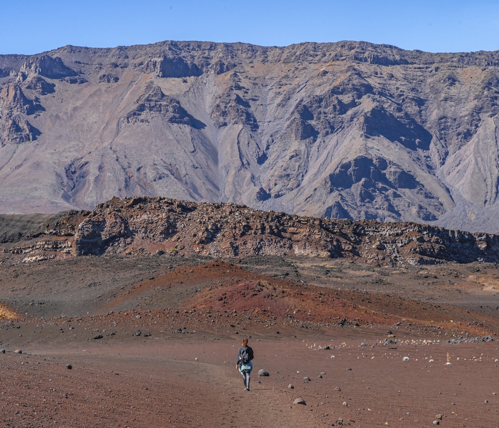 a person is walking in the desert with mountains in the background