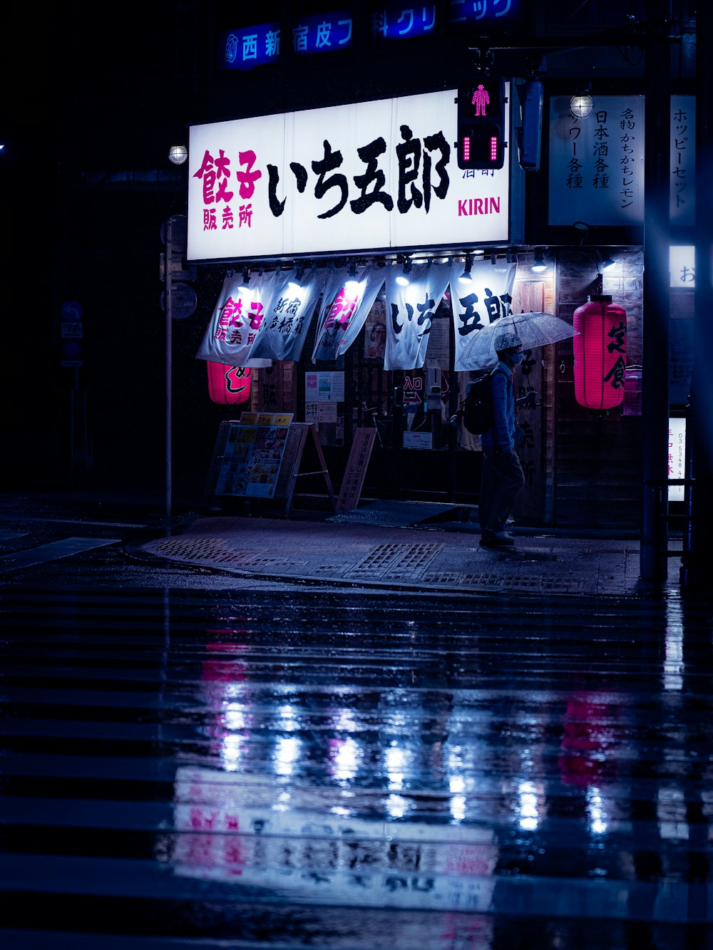 a man walking down a rain soaked street at night