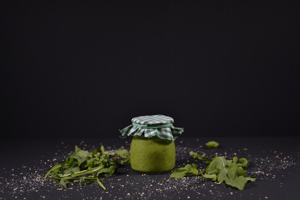a jar filled with green stuff sitting on top of a table