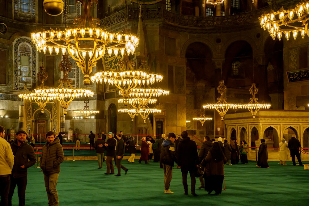 a group of people standing around a room with chandeliers