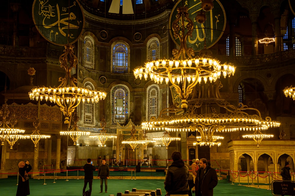 a group of people standing around a room with chandeliers