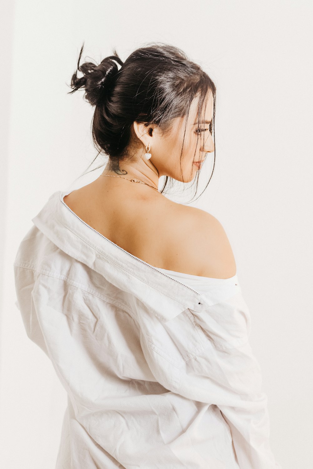 a woman in a white top with a tattoo on her shoulder