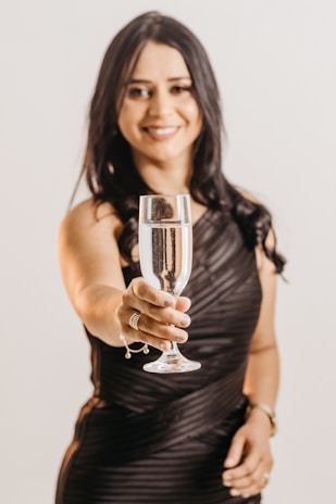 An elegant hostess smiling warmly, dressed in chic evening attire.