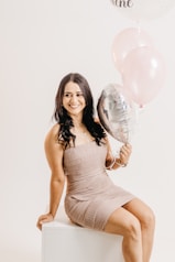 a woman in a dress holding a bunch of balloons
