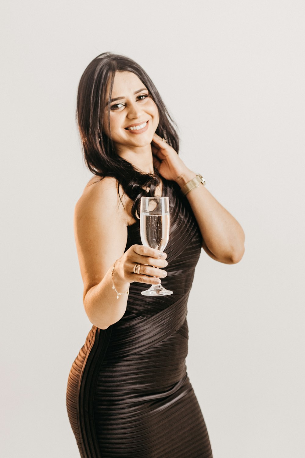 uma mulher em um vestido preto segurando um copo de vinho