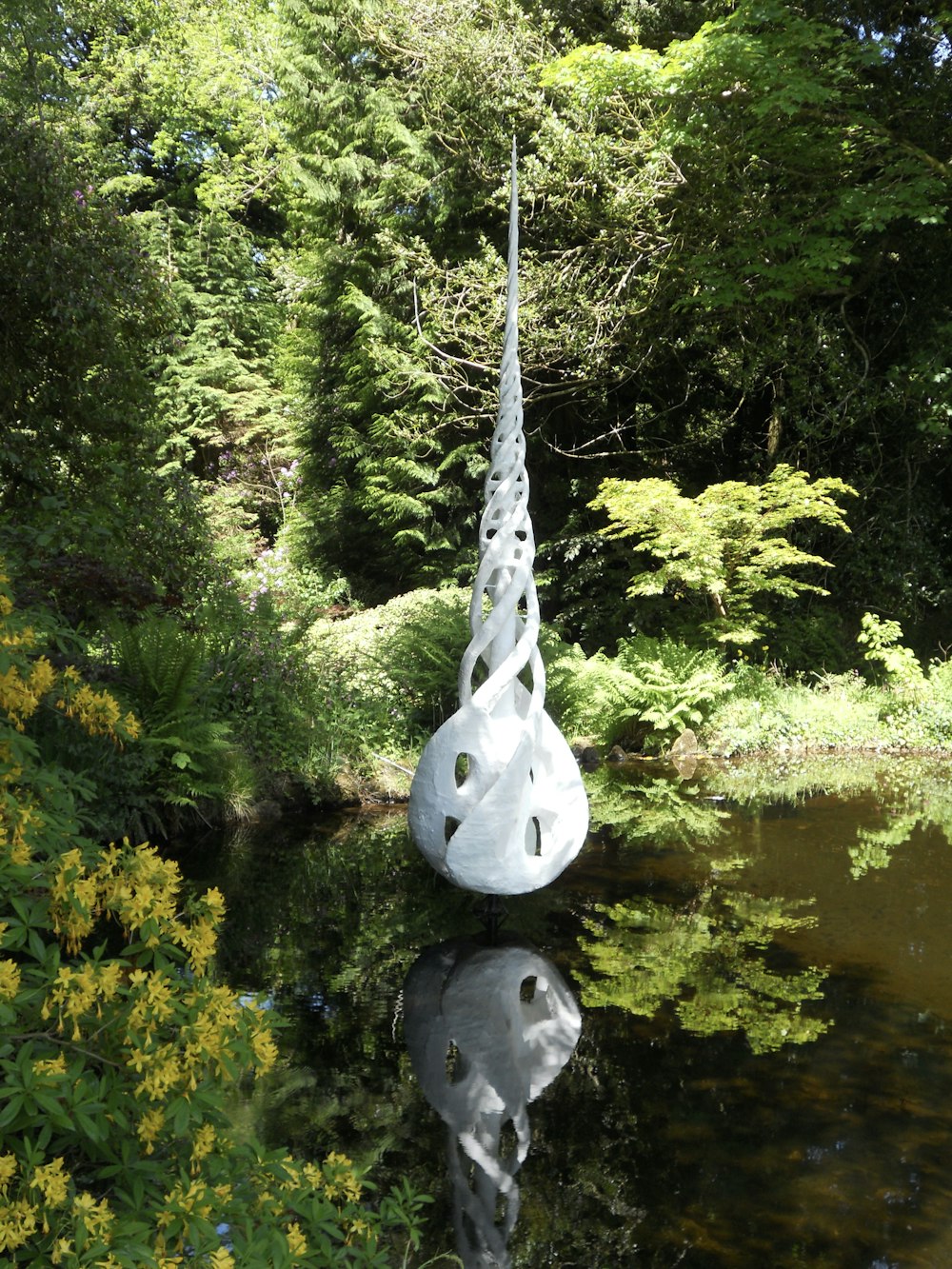 a large white sculpture sitting in the middle of a forest